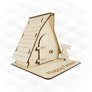 以下が含まれることがあります： ヒンジ付きのドアと側面にウサギの切り抜きが付いた木製のイースターバニーハウス。家のベースには「ハッピーイースター！」という文字が刻まれています。