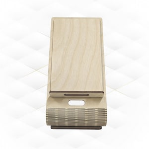 Op de afbeelding: Een houten telefoonstandaard met een decoratief patroon. De standaard is gemaakt van licht hout en heeft een bruine afwerking. De standaard is ontworpen om een telefoon rechtop te houden.