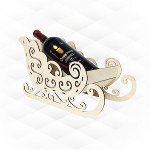 Puede incluir: Un soporte para botellas de vino de madera con forma de trineo con intrincados recortes. Una botella de vino tinto se coloca en el soporte.