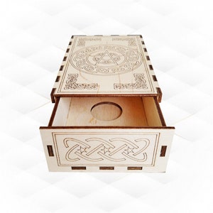 May include: A wooden box with a drawer, featuring a Celtic knot design and a five-pointed star in the center. The box is made of light wood and has a natural finish.