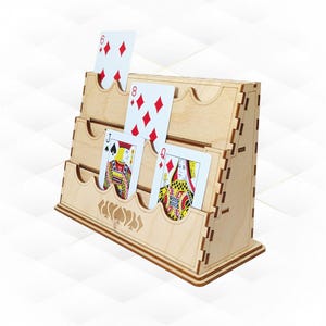May include: A wooden playing card holder with three tiers, each designed to hold multiple cards. The holder displays playing cards, including a six of diamonds, eight of diamonds, a jack of spades, and a queen of diamonds. The holder is made of light-coloured wood.