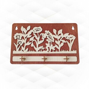 May include: Wooden key holder with a floral design. The key holder is rectangular with a dark brown finish and features a laser-cut floral silhouette in a lighter wood color. Three key hooks are positioned below the floral design.