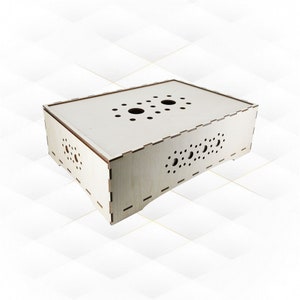 May include: A wooden box with a light brown finish and a pattern of small holes on the sides and top. The box has a rectangular shape and is made of plywood.