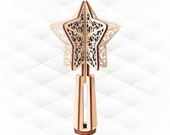 Puede incluir: Un adorno de árbol de Navidad en forma de estrella de madera con intrincados diseños cortados con láser. La estrella está hecha de madera marrón claro y tiene un fondo blanco. La estrella está unida a un poste de madera con una base redonda.