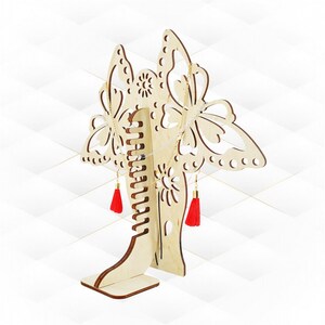 May include: Wooden jewellery stand shaped like a butterfly with red tassels. The stand has slots for necklaces and earrings.