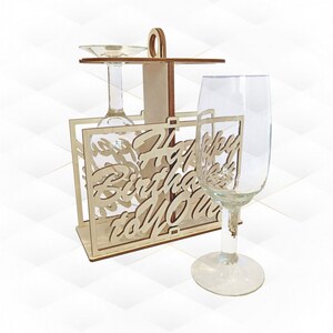 Può includere: Porta bicchieri da vino in legno con le parole "Happy Birthday to Mom" ritagliate. Il porta bicchieri ha due bicchieri da vino attaccati.