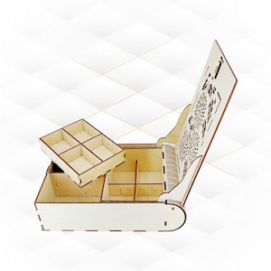 Op de afbeelding: Een houten juwelendoos met een scharnierend deksel met een decoratief uitgesneden ontwerp. De doos heeft meerdere vakken om sieraden of andere kleine voorwerpen op te bergen.