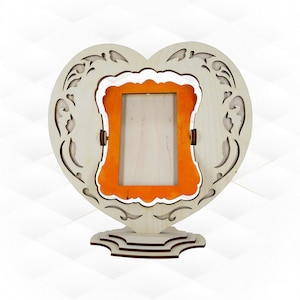 May include: A wooden heart-shaped picture frame with an orange mount and a white border. The frame has intricate cutouts and stands on a tiered base.