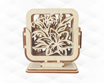 May include: A wooden decorative box with a floral design. The box is made of light-colored wood and features a laser-cut floral pattern on the front. The box is square-shaped and sits on a rectangular base.