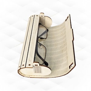 Könnte beinhalten: Ein Brillenetui aus Holz mit einem Scharnierdeckel und einem gemusterten Innenraum. Das Etui ist geöffnet und eine Brille befindet sich darin.