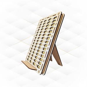 Può includere: Un tabellone di numeri in legno con un supporto. Il tabellone ha 60 quadrati numerati, ognuno con un piccolo disegno di fiore. I numeri sono stampati in un colore marrone chiaro.