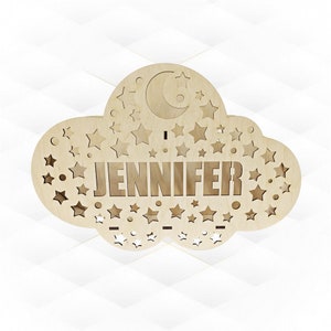 Peut inclure: Une veilleuse en bois en forme de nuage avec une lune croissante et des étoiles découpées. Le nom "JENNIFER" est gravé au centre.