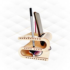 Op de afbeelding: Een houten bureau-organizer met twee niveaus. De bovenste laag heeft een gleuf voor een telefoon en twee gleuven voor pennen. De onderste laag heeft een ruimte voor zonnebrillen. De organizer is gemaakt van licht hout en heeft een natuurlijke afwerking.