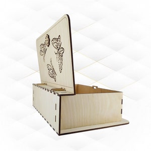 Puede incluir: Una caja de madera con una tapa con bisagras. La tapa tiene un diseño recortado de tres mariposas. La caja está hecha de madera de color claro y tiene un acabado natural.