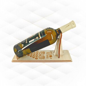 以下が含まれることがあります： ブドウの房とWineという文字がレーザーカットされた、明るい色の木製ワインボトルホルダー。ガラス製の白ワインボトルを斜めに支える構造で、ボトルの首が垂直な木製の支柱部分に乗るように設計されています。