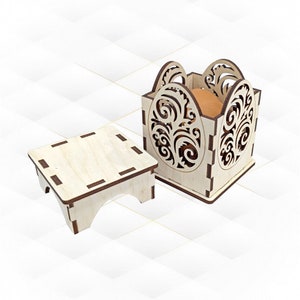 Può includere: Una scatola di legno con un design floreale decorativo e un piccolo supporto in legno. La scatola è aperta e contiene un uovo marrone all'interno.