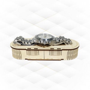 Puede incluir: Un reloj de pulsera plateado con una esfera negra y una correa de metal plateado se muestra en una caja de madera con un patrón decorativo.