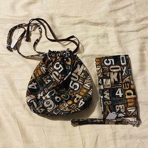 May include: A brown drawstring bag and a matching brown wallet with a black and white print of numbers and letters.