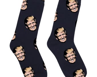 Op de afbeelding: Een paar donkerblauwe sokken met een herhalend patroon van een mannengezicht. De man heeft blond haar en glimlacht.
