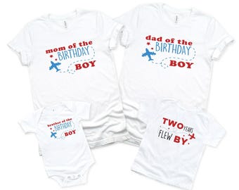 May include: Four white shirts and a bodysuit featuring red and blue text and airplane graphics. The text reads mom of the birthday boy, dad of the birthday boy, brother of the birthday boy, and two years flew by with dashed flight paths.