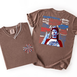 May include: Two brown t-shirts with a graphic print. One shirt is folded with a silver chain necklace and a firework design. The other shirt has a graphic of a man with text that reads "You Don't Have No Spleen Splitters" and "Whisker Biscuits".