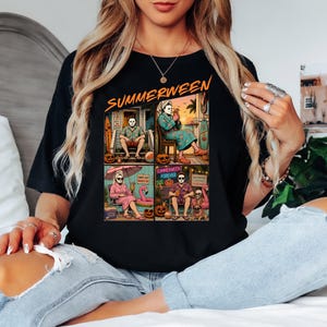 May include: A black t-shirt featuring a graphic print with the text "SUMMERWEEN" at the top. The design is divided into four panels showing characters in summer settings with pumpkins, beach gear, and tropical drinks, blending horror and vacation themes.