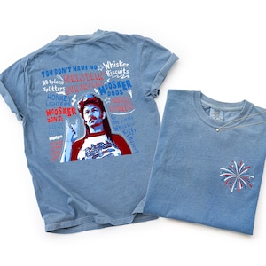 May include: Two light blue t-shirts. One features a graphic of a man with text that reads "YOU DON'T HAVE NO...WHISTLER...MOOSKER..." The other shirt has a small embroidered firework design. A delicate necklace is draped on the second shirt.