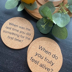 May include: Two cork coasters with black text. The first coaster says "When was the last time you did something for the first time?" The second coaster says "When do you truly feel alive?"