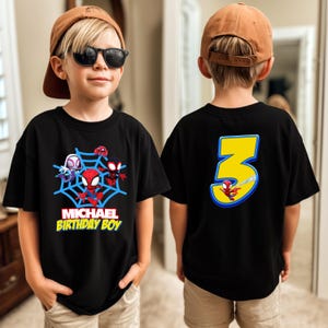 Puede incluir: Camiseta negra con personajes de Spider-Man y un dise&ntilde;o de telara&ntilde;a azul. La parte delantera dice "MICHAEL BIRTHDAY BOY". La parte trasera tiene un gran n&uacute;mero 3 amarillo con un gr&aacute;fico de Spider-Man.