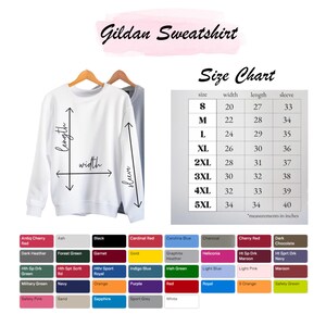 Peut inclure: Sweat-shirt Gildan blanc sur un cintre en bois, avec un tableau des tailles et des options de couleurs. Le tableau des tailles indique les mesures en pouces pour les tailles S &agrave; 5XL. Les options de couleurs incluent le noir, le rouge et le vert.
