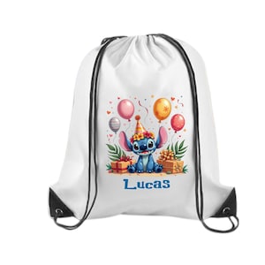 May include: White drawstring backpack featuring a cartoon character with blue fur, wearing a party hat, surrounded by balloons and gifts. The name "Lucas" is printed in blue. Black drawstrings and accents.