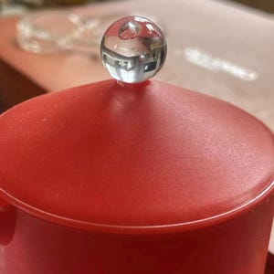 May include: Red coffee pot with a clear glass knob on the lid.