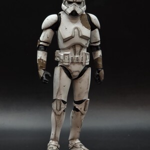 以下が含まれることがあります： スターウォーズのストームトルーパーの、立ち姿の精巧なアクションフィギュア。フィギュアは主に白で、黒と茶色のアクセントがあり、使い古されたディテールが特徴です。ヘルメットとアーマーは精巧にデザインされており、象徴的な外観を捉えています。