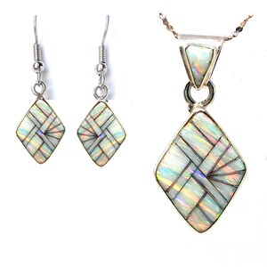 May include: A jewelry set featuring a pendant necklace and matching earrings. The set has a silver-tone metal setting and features a geometric design with iridescent, opalescent stones. The earrings are drop style, and the pendant is diamond-shaped.