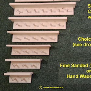 May include: Five wooden coat peg racks with a top shelf. The racks are in different sizes and are made of natural wood. The text "Shaker Style Coat Peg Racks with Top Shelf" is written in yellow on a green background. The text "Choice of Sizes (see drop down menu)" is written in yellow on a green background. The text "Fine Sanded (ready to paint) or Hand Waxed Polished" is written in yellow on a green background.