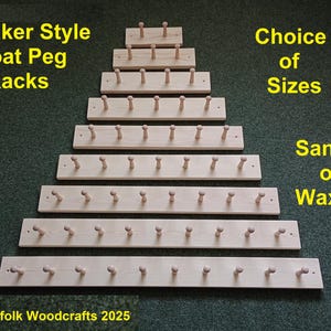 May include: A set of seven wooden coat peg racks in various sizes, arranged in a pyramid shape. The racks are made of natural wood and have a shaker style. The text "Shaker Style Coat Peg Racks" is at the top of the image. The text "Choice of Sizes" is on the right side of the image. The text "Sanded or Waxed" is at the bottom right of the image. The text "C) Suffolk Woodcrafts 2025" is at the bottom left of the image.