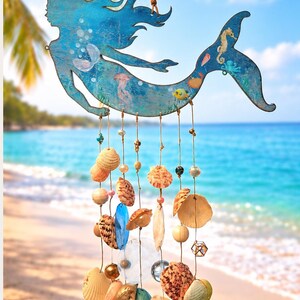May include: A blue wooden mermaid cutout hanging mobile featuring painted sea life illustrations. Multiple strands of twine are suspended from the mermaid, decorated with various natural seashells, clear glass beads, and small wooden spheres.