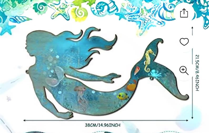 May include: A blue-toned wooden mermaid wall cutout featuring a painted sea life design on the tail, including a seahorse, octopus, and fish. The piece measures 21.5 cm by 38 cm, with a watercolor-style border of shells and starfish.