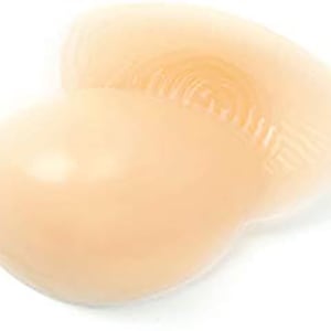 May include: A pair of nude silicone breast enhancers. The enhancers are shaped like a half-circle and have a smooth, seamless surface.
