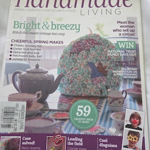 May include: A magazine cover titled "Handmade Living" features a tea cozy with a floral pattern and an illustration of a person with an umbrella. The cover also includes text about crafts, gardens, and creative ideas.