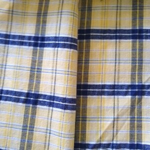 Puede incluir: Tela de cuadros amarillos y azules con textura tejida.