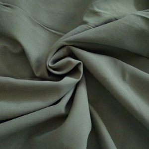 May include: A close-up of a smooth, dark gray fabric with soft folds and wrinkles.