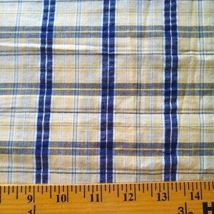 Puede incluir: Primer plano de una tela de cuadros amarilla y azul con una regla que mide 38 cm.