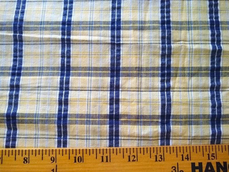 Puede incluir: Primer plano de una tela de cuadros amarilla y azul con una regla que mide 38 cm.