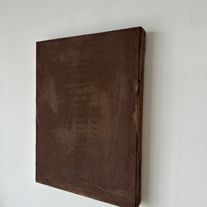 May include: A brown square canvas painting with a textured surface.