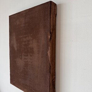 May include: A brown canvas painting with a textured surface. The painting is mounted on a wooden frame.