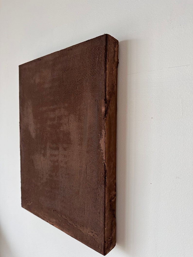 May include: A brown canvas painting with a textured surface. The painting is mounted on a wooden frame.