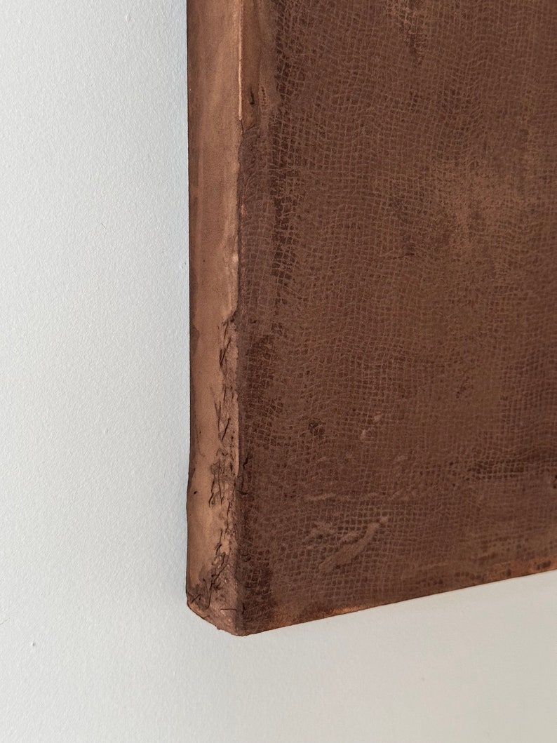 May include: Close-up of the edge of a brown canvas painting. The canvas has a textured surface and is stretched over a wooden frame.