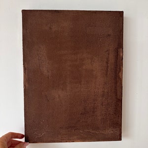 May include: A brown canvas painting with a textured surface.