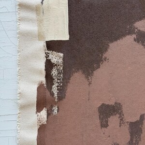 May include: Abstract art canvas with a raw edge. The artwork features a palette of brown, beige, and off-white brushstrokes. The canvas has a textured appearance, with visible paint application and a raw, unfinished edge.
